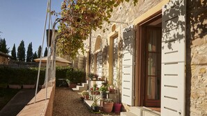 A stone building with a wooden deck, potted plants, and a clear sky. - The Casaloni app. Tower (Panzano In Chianti)