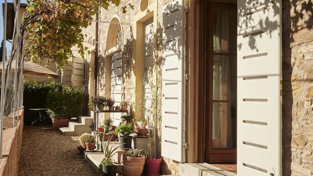 A stone building with a gravel pathway, potted plants, and a wooden door. - The Casaloni app. Tower (Panzano In Chianti)