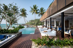 A poolside area with lounge chairs and a view of the ocean. - Ahu Bay (Ahungalla)