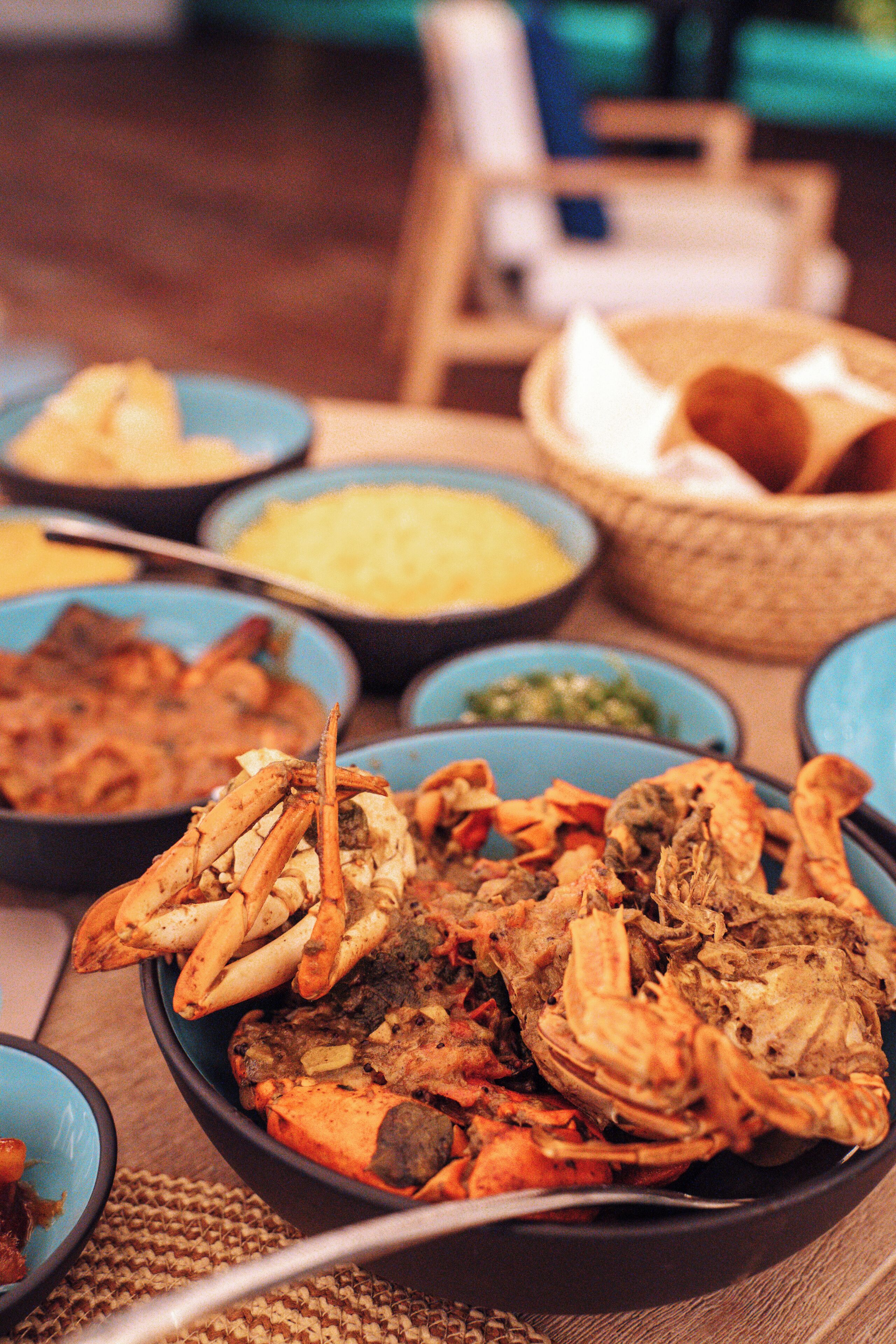 A table with various dishes, including seafood and other foods, in blue and black bowls.