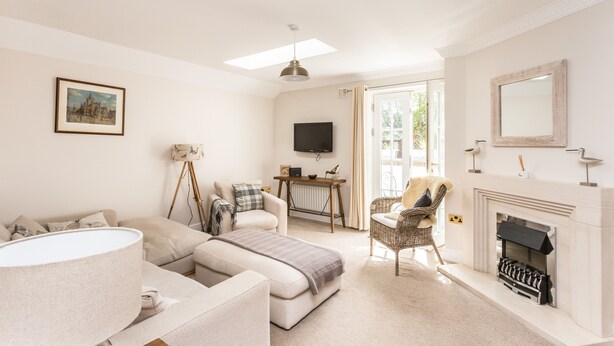 A living room with a sofa, armchair, and a fireplace. - An Sulaire (North Berwick)