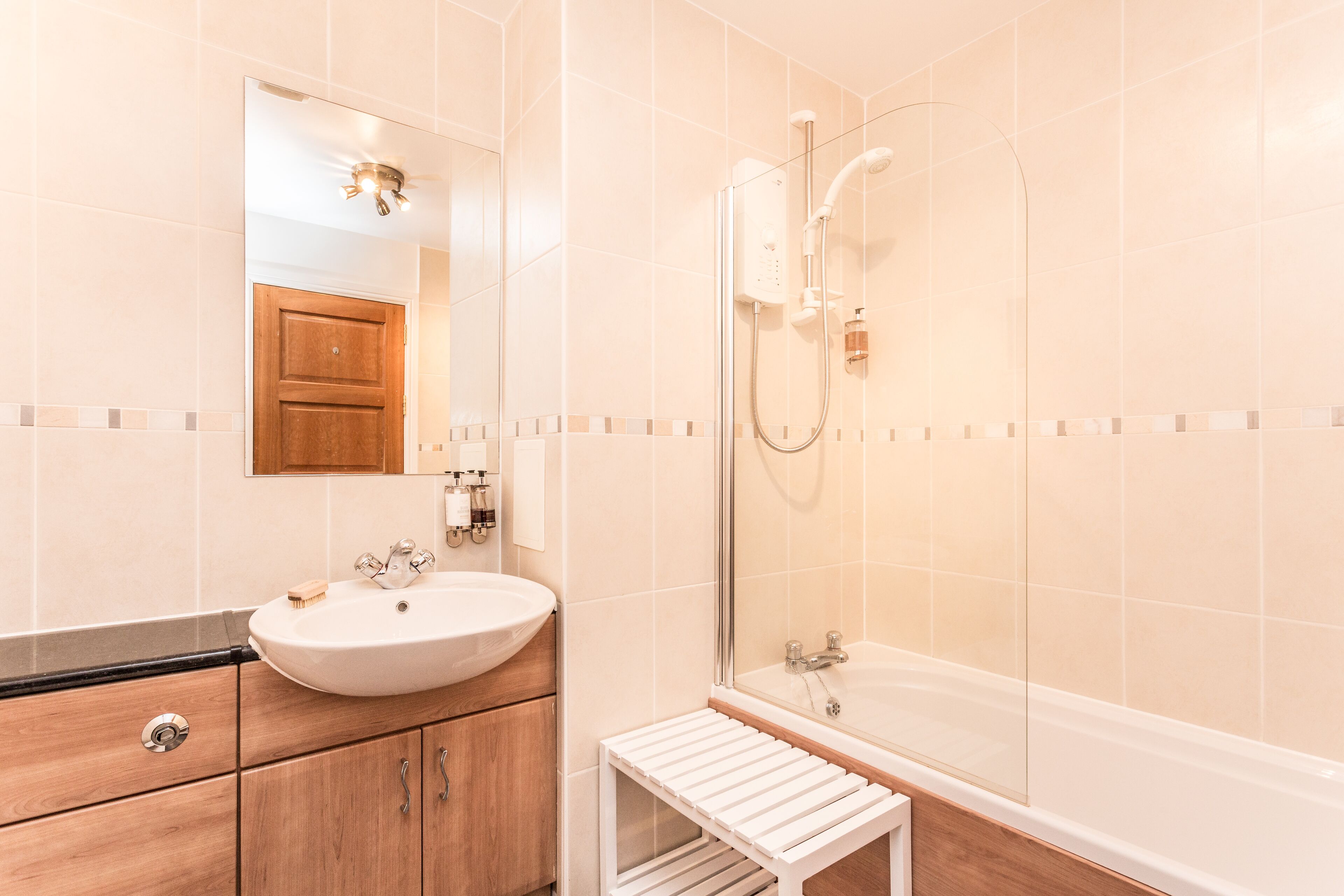 A modern bathroom with a sink, mirror, and shower.
