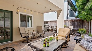 Un patio al aire libre con asientos, una mesa y luces colgantes.
