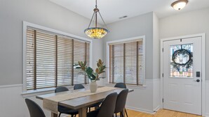 A dining area with a wooden table, black chairs, a vase with plants, and a stained glass pendant light. - Red Barn Roost • Cozy Stay Near Downtown (Loveland)