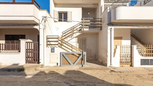 A two-story building with a staircase leading to the upper floor, a gated entrance, and a clear sky. - 2658 Appartamento Cecilia by Barbarhouse (Porto Cesareo)
