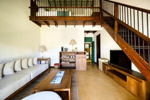 A spacious living room with a wooden staircase, a sofa, a coffee table, and a television.
