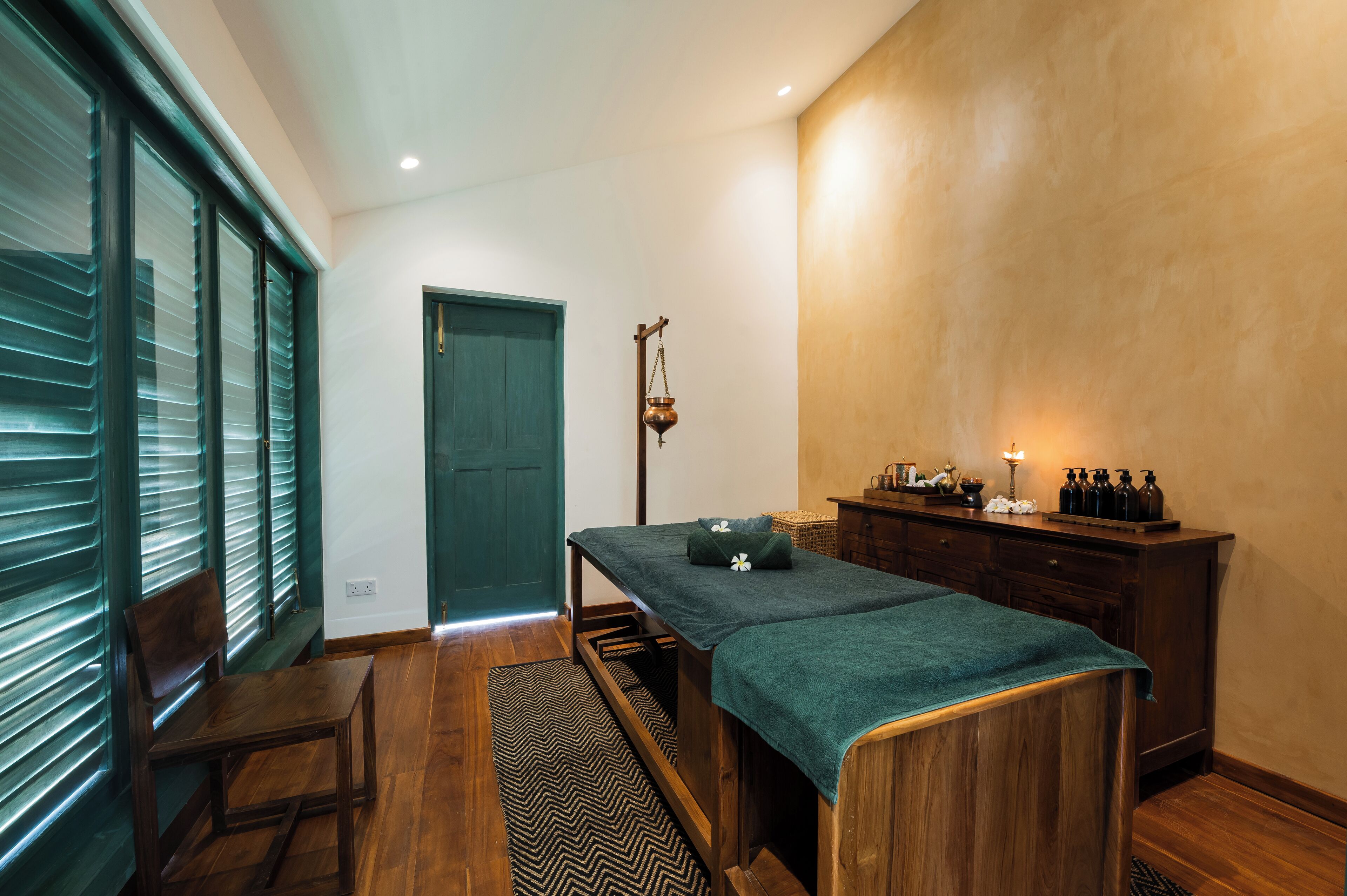 A room with a wooden bench, a massage table, and a small cabinet with bottles.