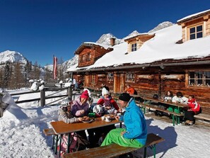 A wooden cabin with a snow-covered roof, a wooden fence, and a clear blue sky. - Vierbettzimmer mit Bad, WC - HP - Golf- und Skipension Krug (Haus)