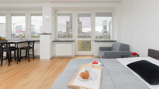 Un apartamento moderno con comedor, cocina y una cama grande con vistas a la ciudad.