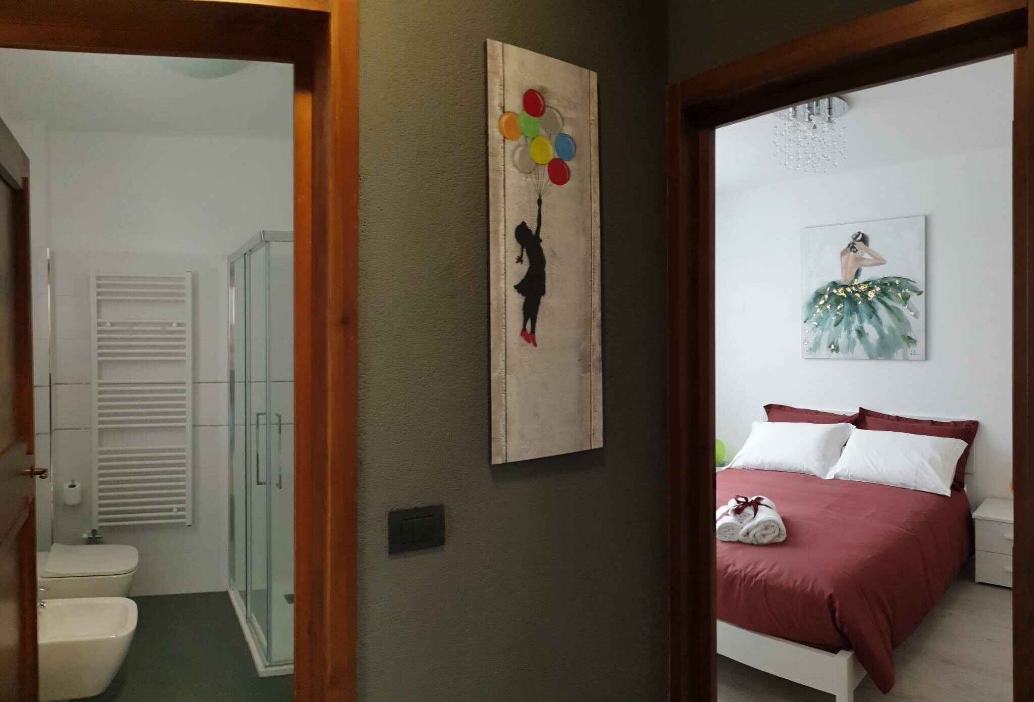 Ein Hotelzimmer mit Dusche, einem Bett mit roter Bettwäsche und einem Gemälde an der Wand.