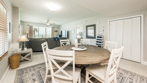 Een eetgedeelte met een ronde houten tafel, witte stoelen en een kroonluchter.