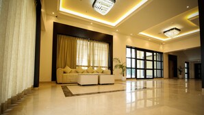 A spacious lobby with a modern sofa, a staircase, and a large window. - Enrise by Sayaji Rewa (Huzur)