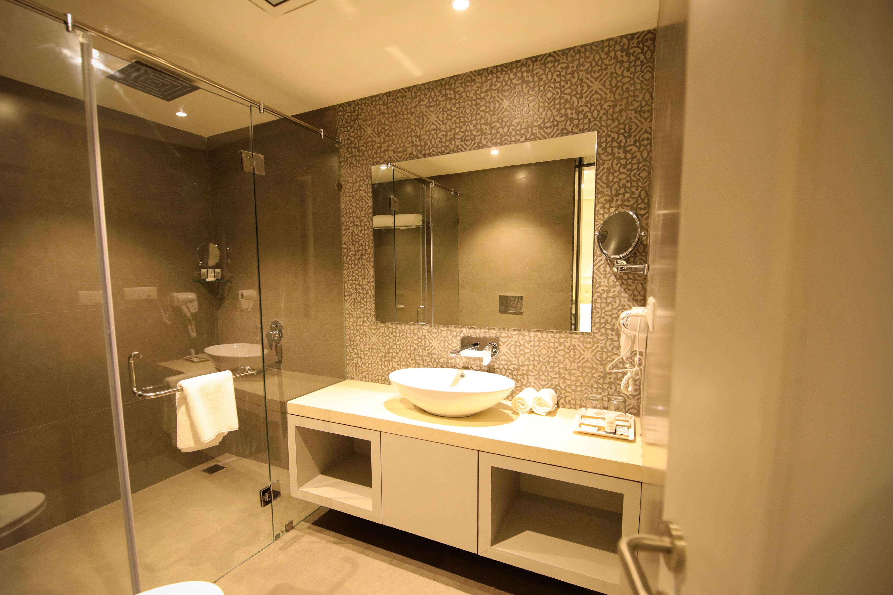 A modern bathroom with a glass-enclosed shower, a large sink, and a mirror above the vanity.