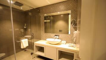 A modern bathroom with a glass-enclosed shower, a large sink, and a mirror above the vanity.