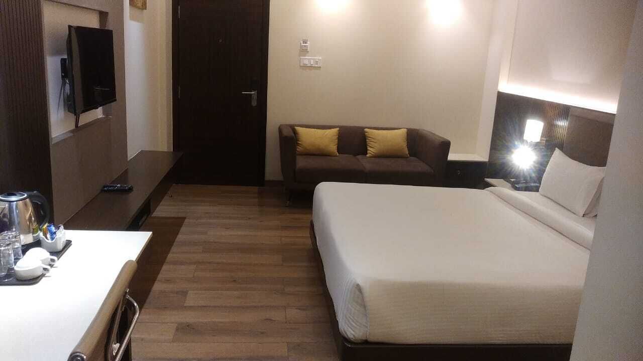 Une chambre d’hôtel comprenant un lit, un canapé, une télévision et une table de chevet avec une lampe.