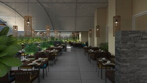 A spacious outdoor dining area with multiple tables and chairs, surrounded by greenery and under a large tent-like structure. - Enrise by Sayaji Rewa (Huzur)