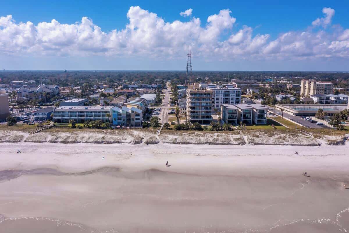 A coastal cityscape with modern buildings, a beach, and a clear sky.