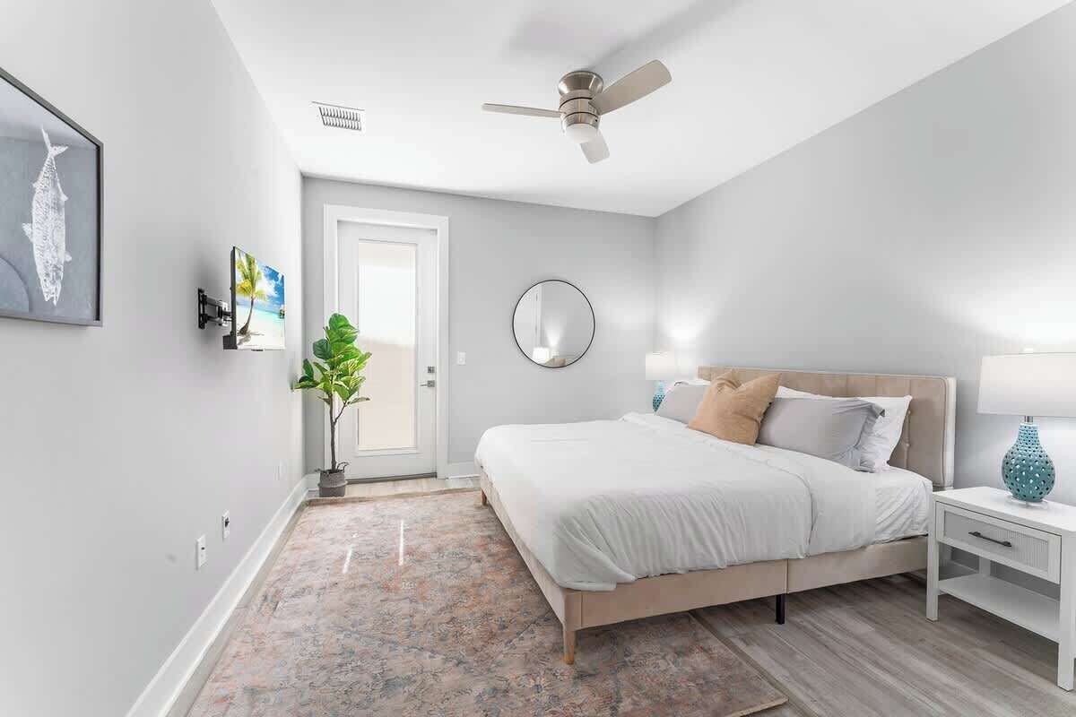 Un dormitorio con cama, mesita de noche, lámpara, ventilador de techo y una puerta.