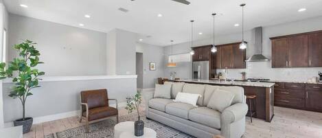 A modern kitchen with dark wooden cabinets, a central island, and pendant lighting.