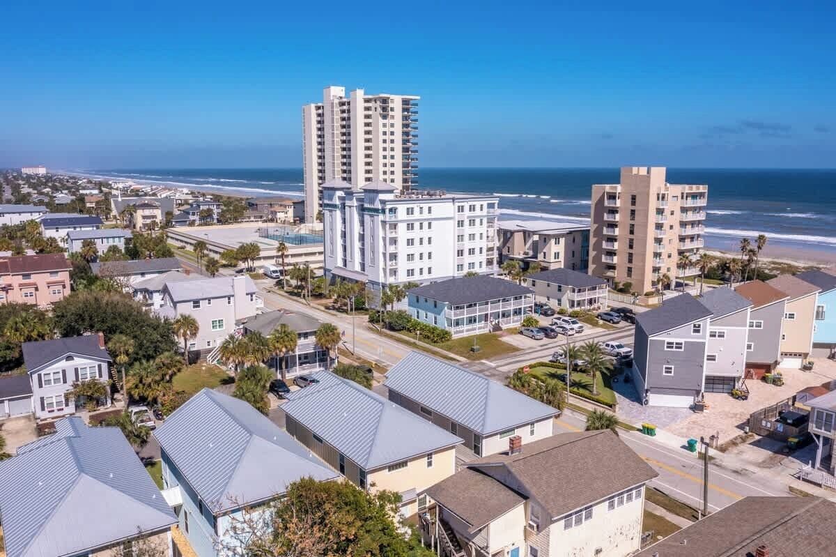 A coastal residential area with multi-story buildings, a clear view of the ocean, and a mix of single and multi-unit homes.