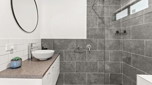 Un bany modern amb un vàter blanc, una petita planta en test i un mirall.