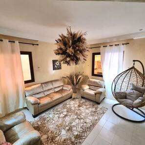 A living room with a sofa set, a hanging chair, and a decorative plant arrangement. - Apartment in the heart of Gueliz, Marrakech (Marrakech)
