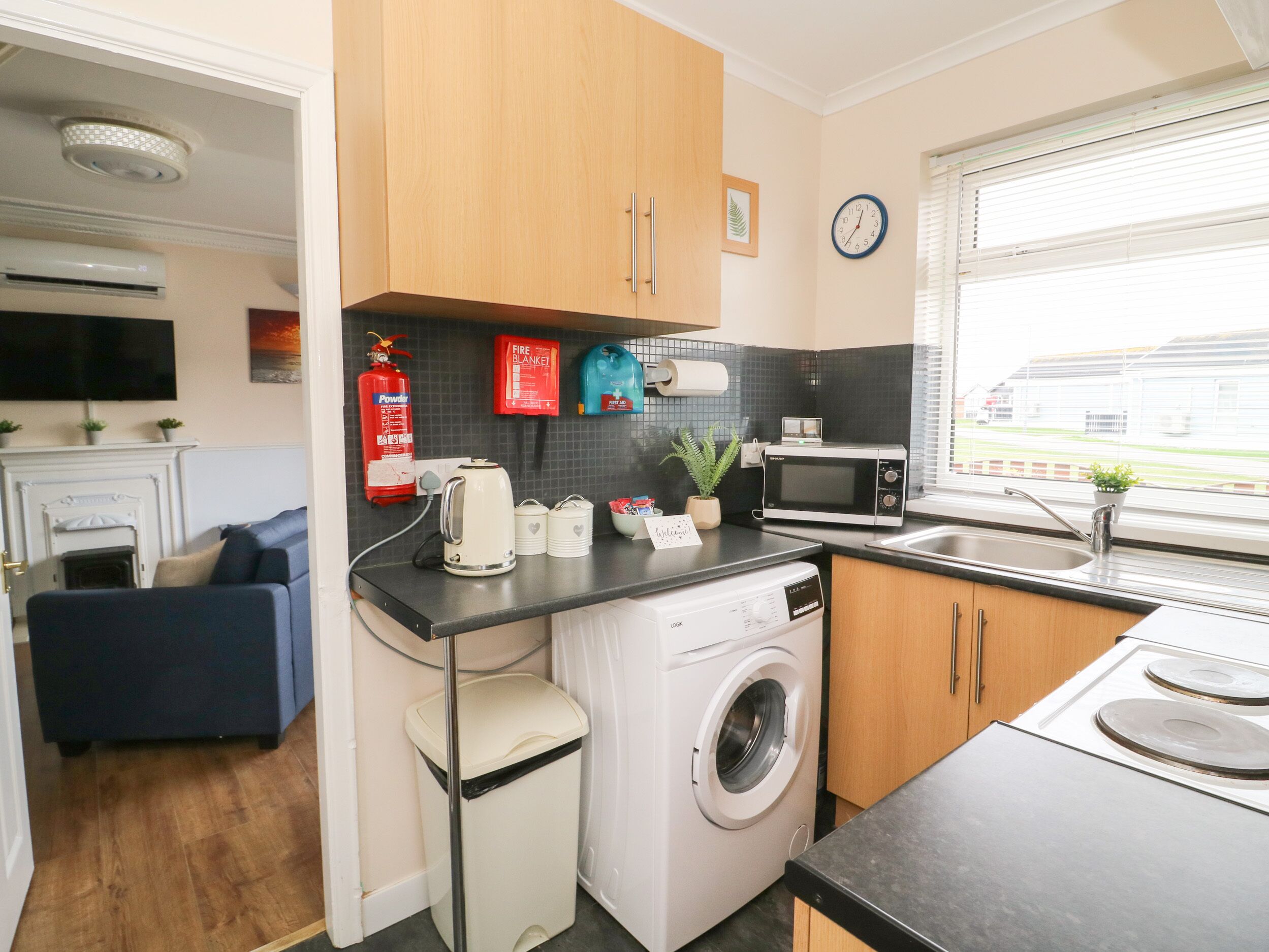 A compact kitchen with a washing machine, microwave, and a small sink.