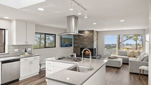 Een moderne keuken met een centraal eiland, een open haard en uitzicht op de omgeving.