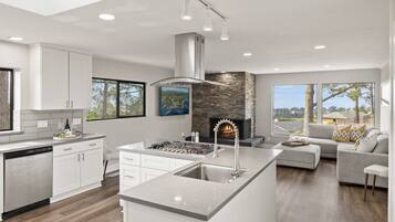 Una cocina moderna con una isla central, una chimenea y vistas al exterior.