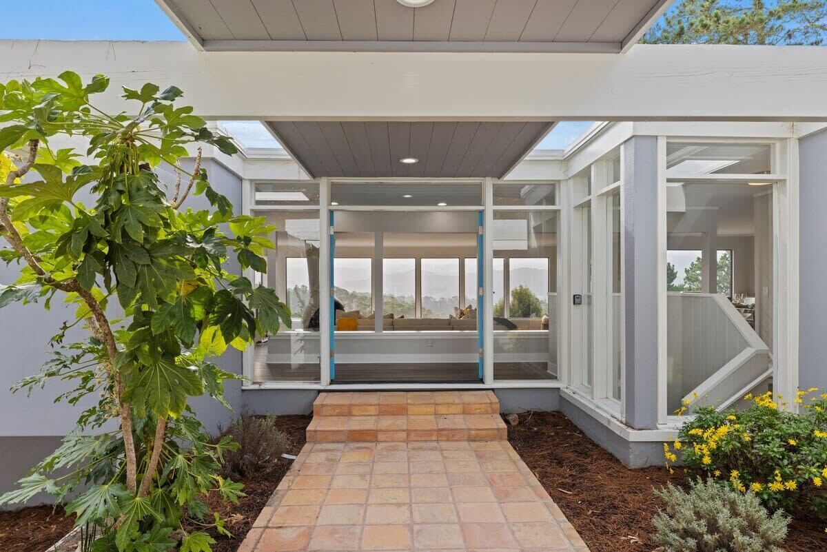 Una casa moderna con puerta de cristal, un patio y vistas al paisaje.