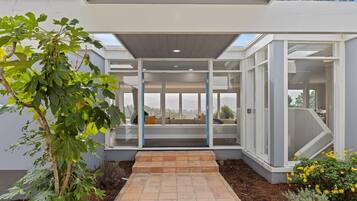 Una casa moderna con puerta de cristal, un patio y vistas al paisaje.
