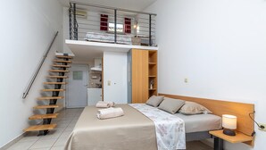 Quarto com uma cama beliche, escrivaninha, luminária e um pequeno espaço de cozinha.