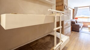 A bunk bed with a ladder, wooden walls, a sofa, and a large window in a room. - Le Borsat (Val Claret) by Interhome (Tignes)
