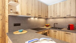 A modern kitchen with wooden cabinets, a black countertop, and a red coffee machine. - Le Borsat (Val Claret) by Interhome (Tignes)