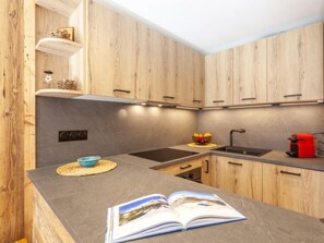Een koelkast, een oven, een vaatwasser, kookgerei, borden en bestek