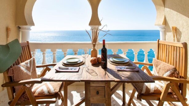 A wooden table set for two with a view of the sea through arched windows. - Sea Suite by Interhome (Almuñécar)
