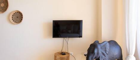 A room with a mounted TV, a wicker basket, and a statue of an elephant.
