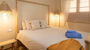 A bedroom with a bed, bedside lamps, a window with curtains, and a bench. - Sea Suite by Interhome (Almuñécar)