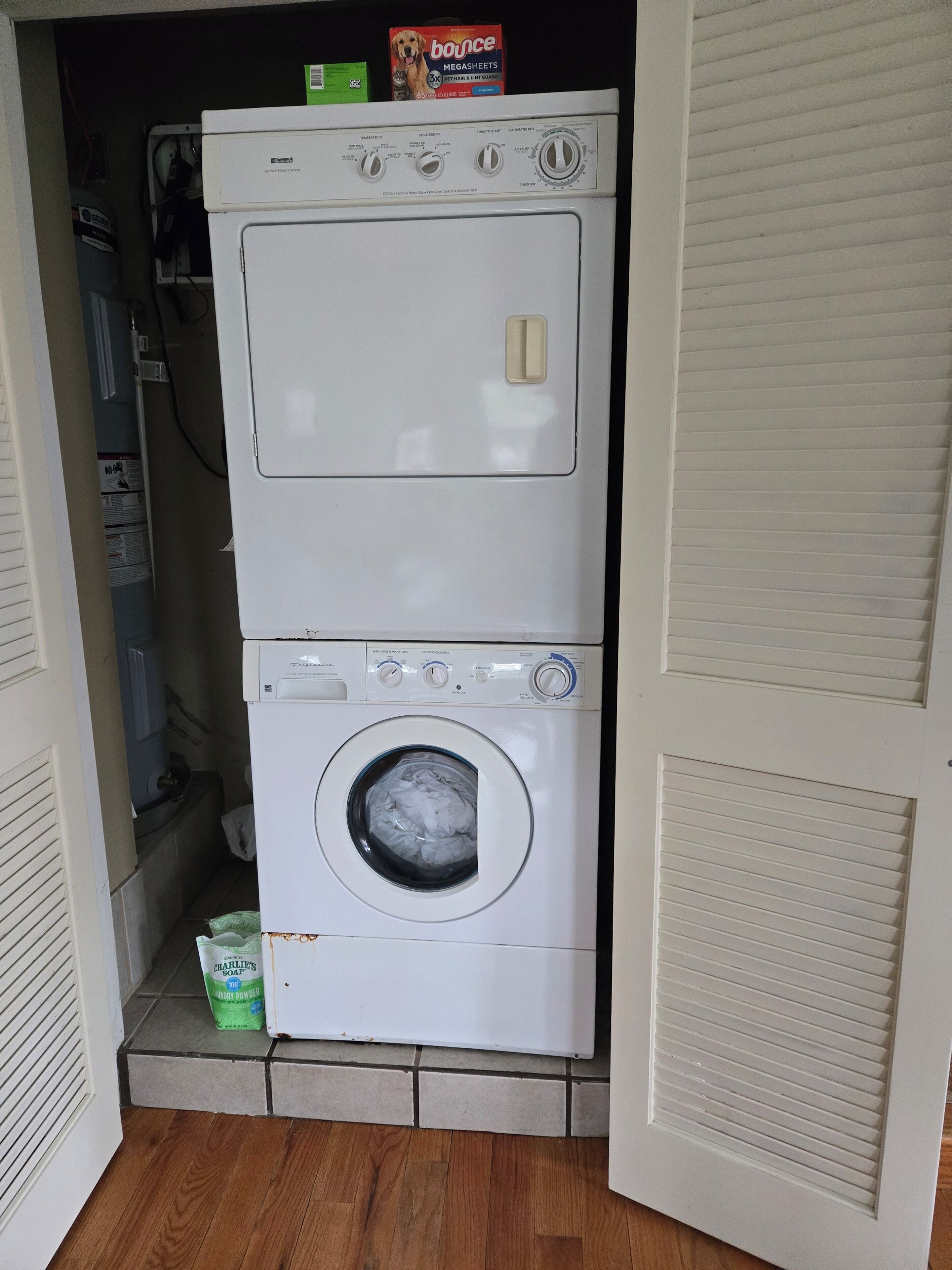 A front-loading washing machine and dryer in a laundry room with a wooden floor.