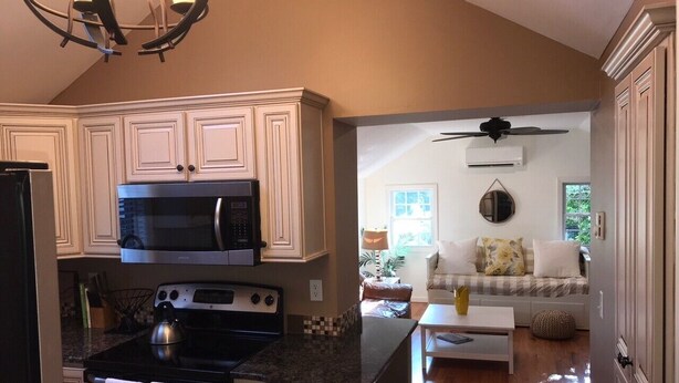 A kitchen with a microwave, stove, and granite countertop. There is a dining area with a sofa and a coffee table.