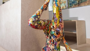 A modern interior with a large abstract sculpture in a yoga pose, a reception desk, and large windows. - E-kilibrio Hotel & Apart-Suites (Madrid)