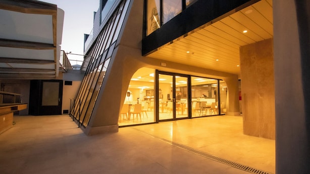 A modern building with a glass entrance leading to an interior space with tables and chairs. - E-kilibrio Hotel & Apart-Suites (Madrid)