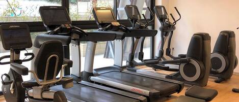 A gym with treadmills, elliptical machines, and weight benches.