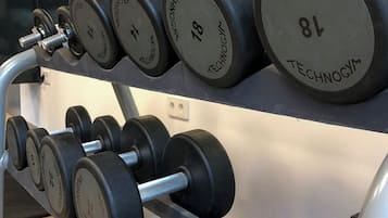 Estante con mancuernas en un gimnasio, con pesas que van de 10 a 22 kilogramos.