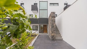 Un bâtiment moderne doté d’un escalier et d’une porte donnant sur une entrée abritée.