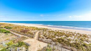 Een strand met een houten omheining en een pad naar het water.