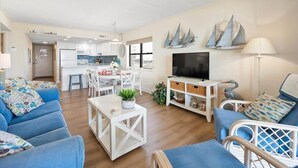 Een moderne woonkamer met een bank, tv-meubel en eethoek.
