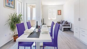 Un espace repas moderne avec une table blanche, des chaises violettes et une plante en pot.