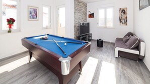 Un salon moderne avec une table de billard, un canapé et un téléviseur.