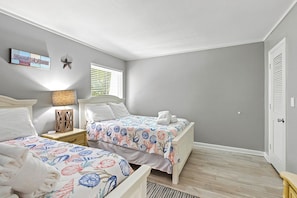 Une chambre avec deux lits, une table de chevet, une lampe et un élément décoratif mural.
